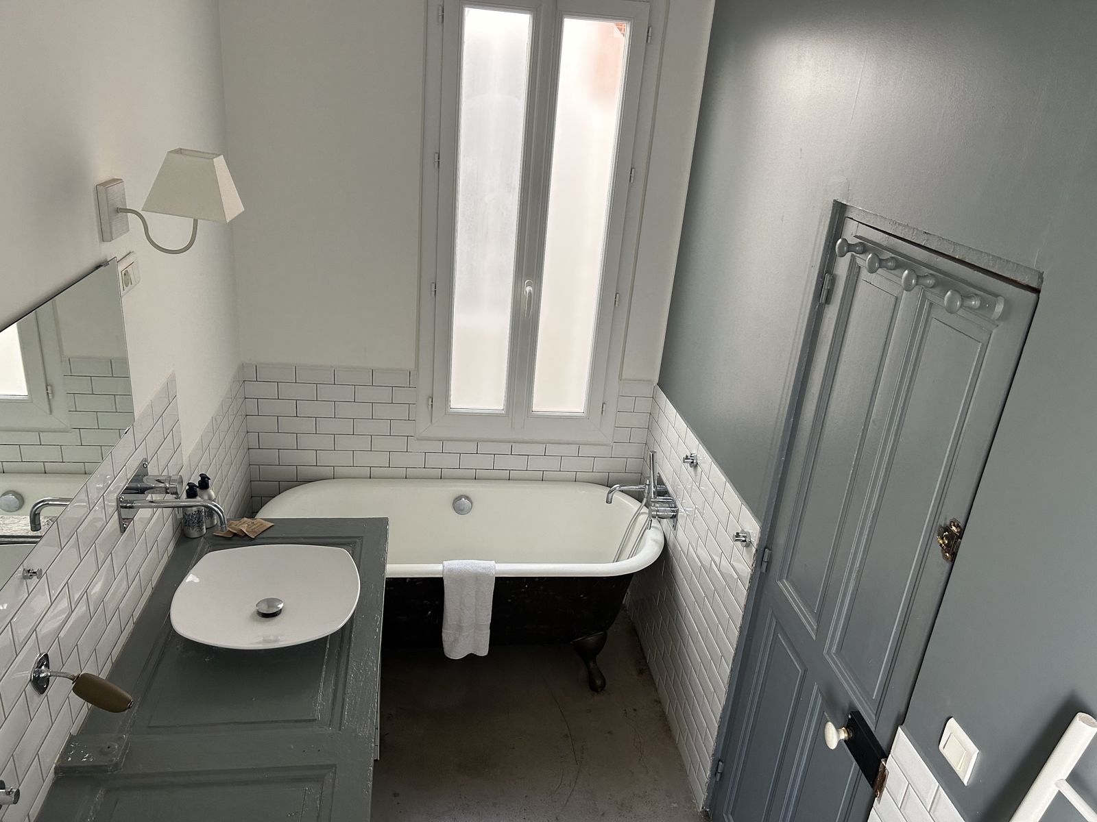 Salle de bain avec baignoire noire sur pieds et carrelage métro blanc