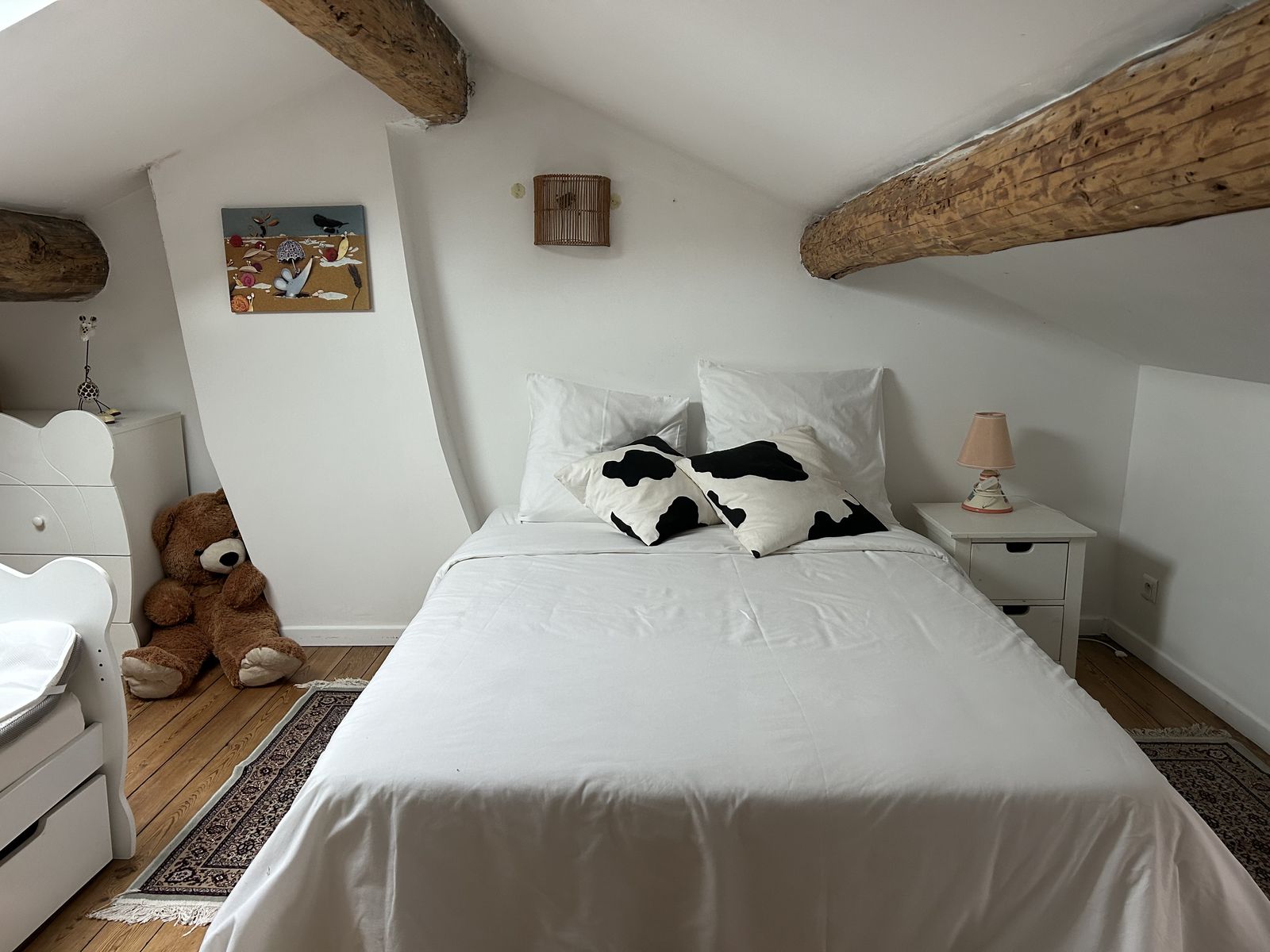 Chambre mansardée cosy avec poutres, lit et grand ours en peluche