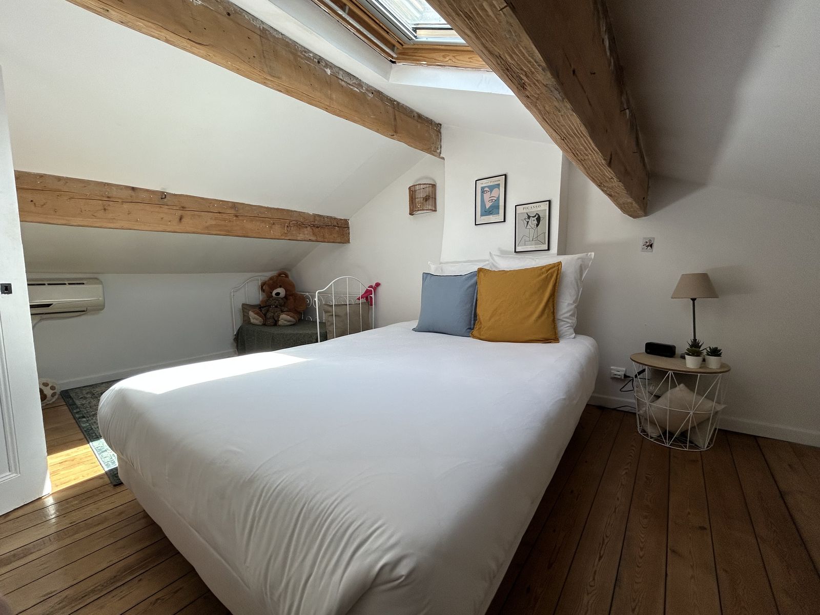 Chambre mansardée avec poutres apparentes et affiches Picasso
