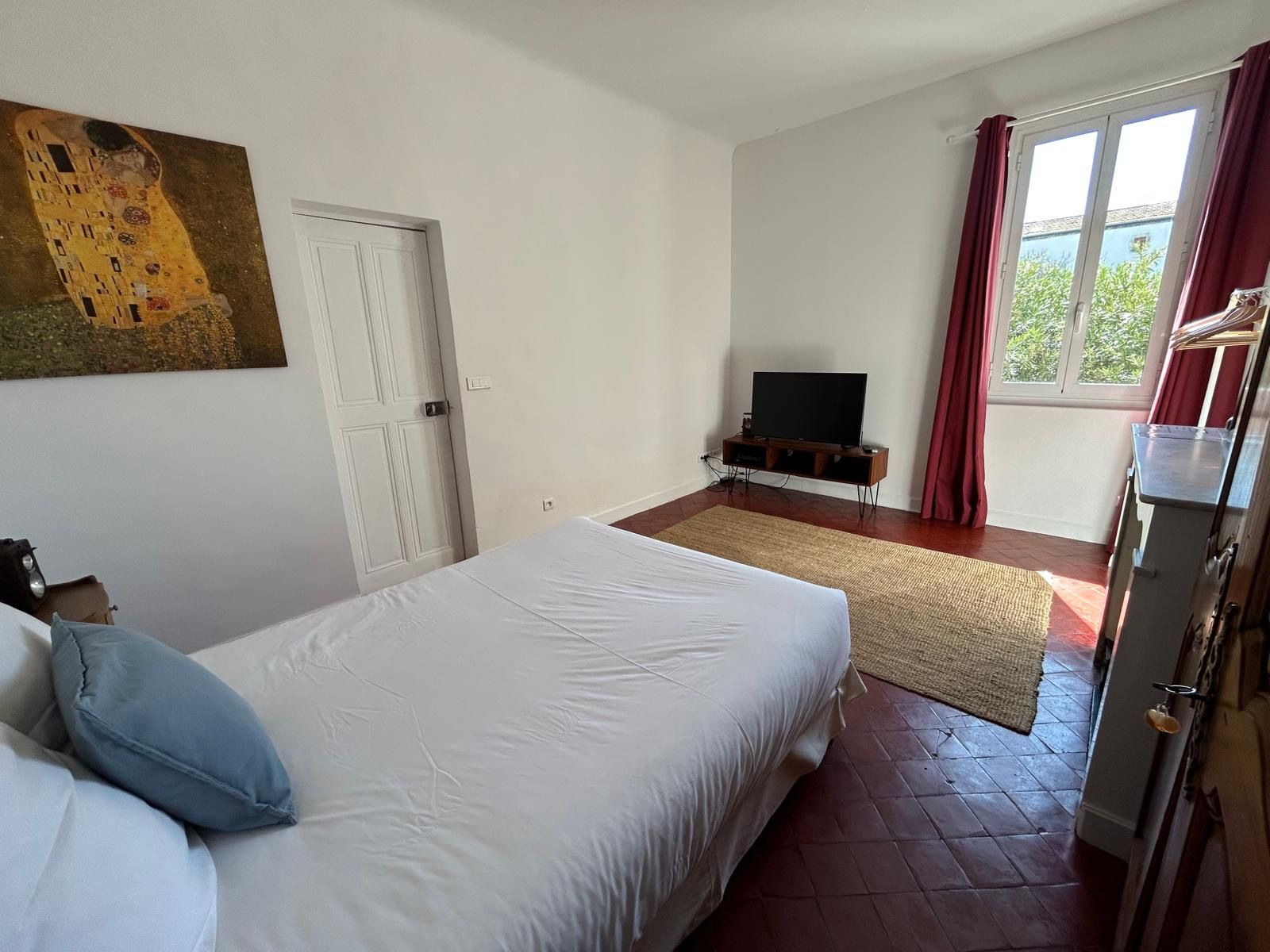 Chambre avec reproduction du Baiser de Klimt et rideaux rouges