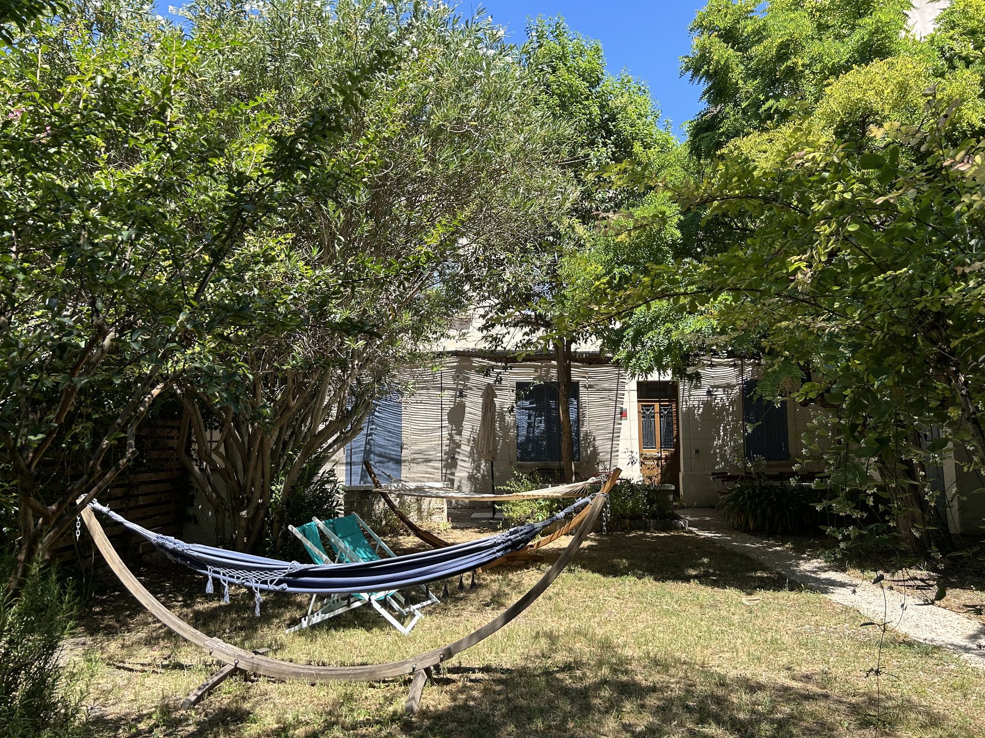 Jardin arboré avec hamac suspendu entre les arbres et pelouse verdoyante
