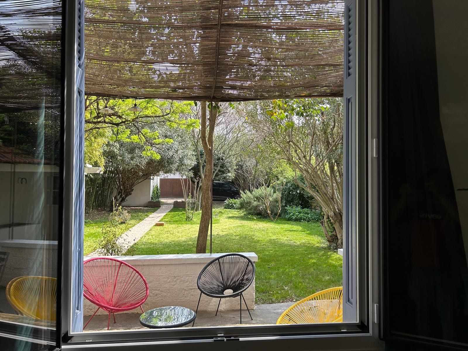 Vue sur le jardin et la terrasse depuis la fenêtre du salon