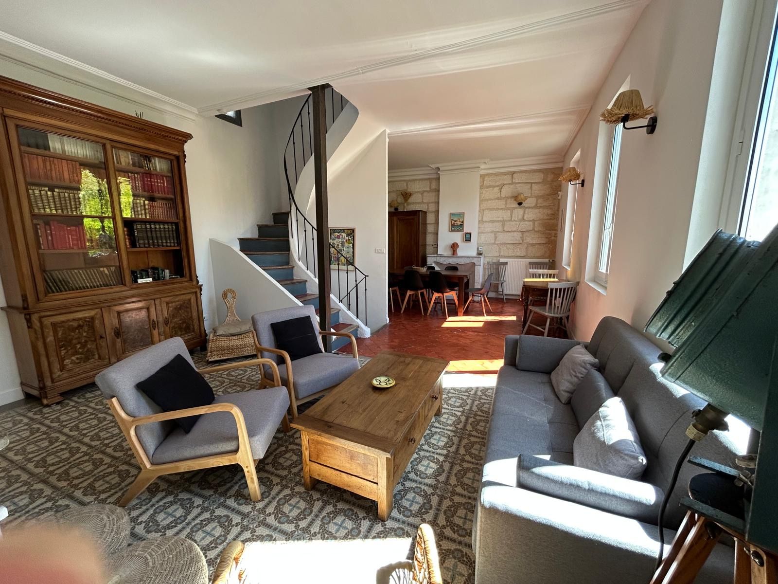 Salon lumineux avec bibliothèque ancienne, escalier en colimaçon et carreaux de ciment